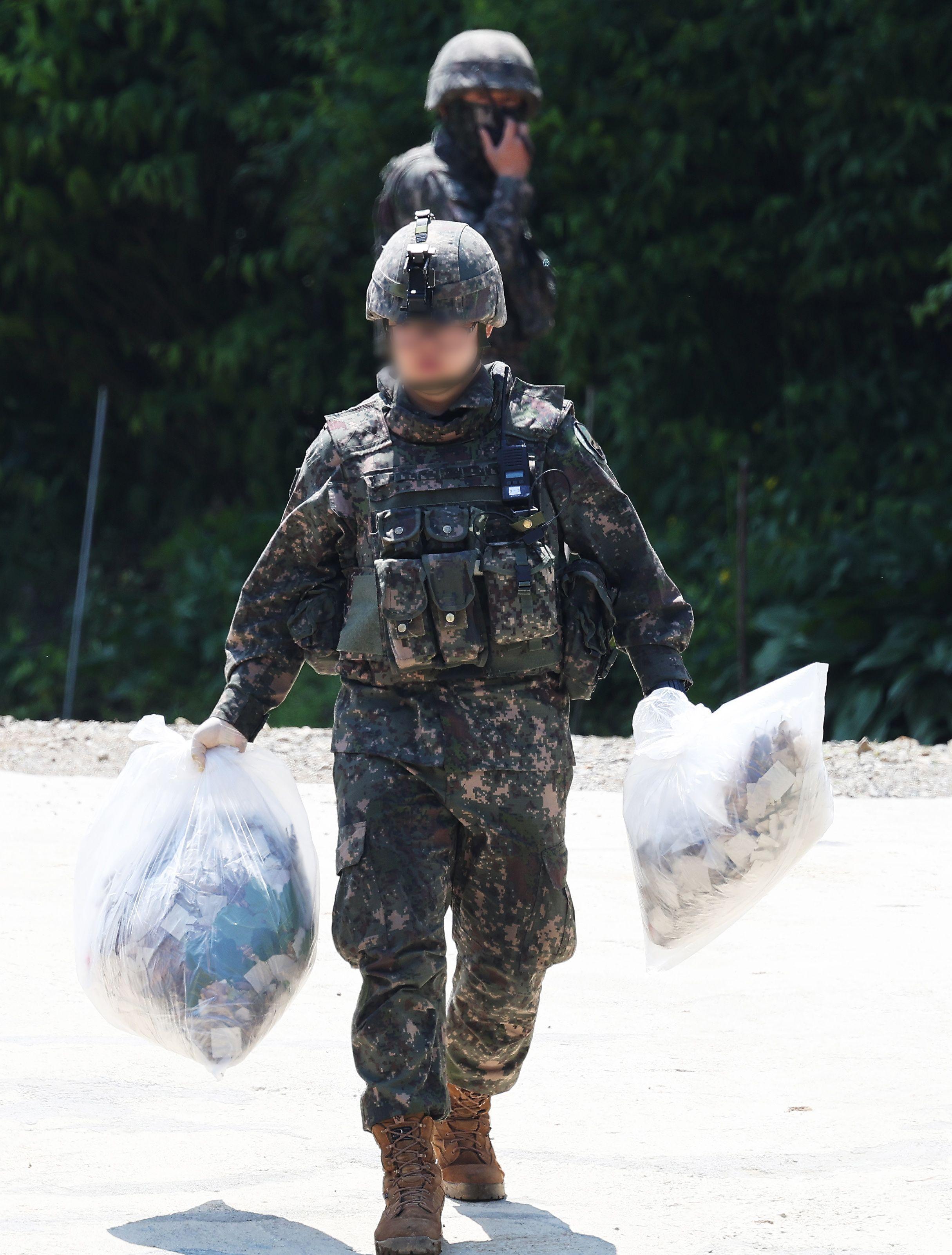 Soldado sul-coreano carregando duas sacolas brancas com lixo