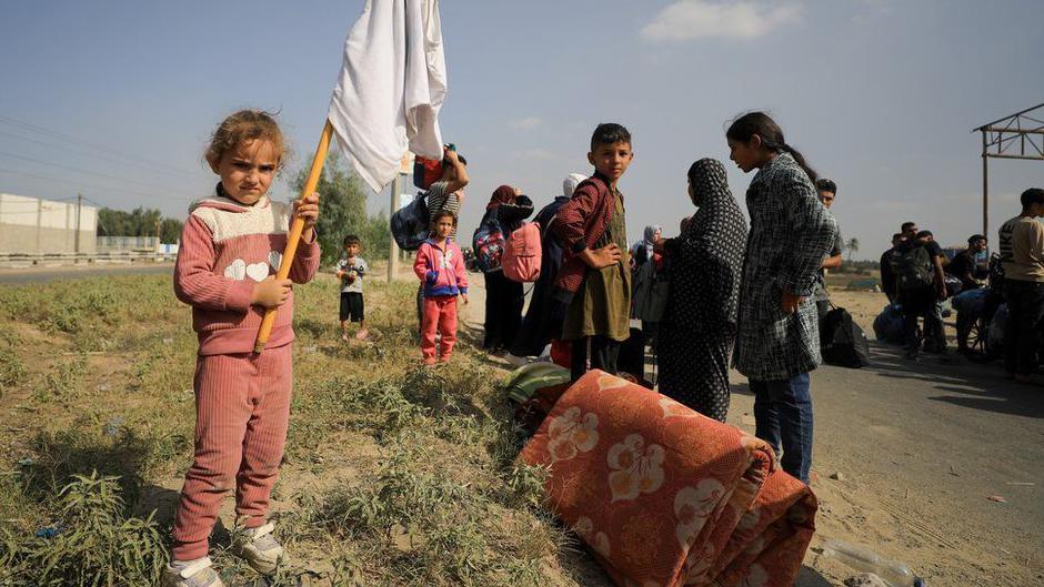 فتاة صغيرة تحمل راية بيضاء مرتجلة بينما تتوقف عائلتها المتجهة جنوبا للراحة على طريق صلاح الدين