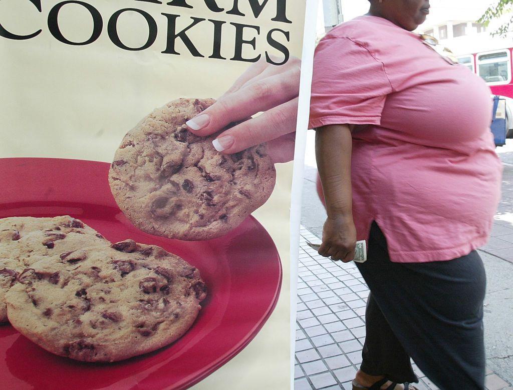 Mujer con obesidad al lado de un cartel de galletas dulces.