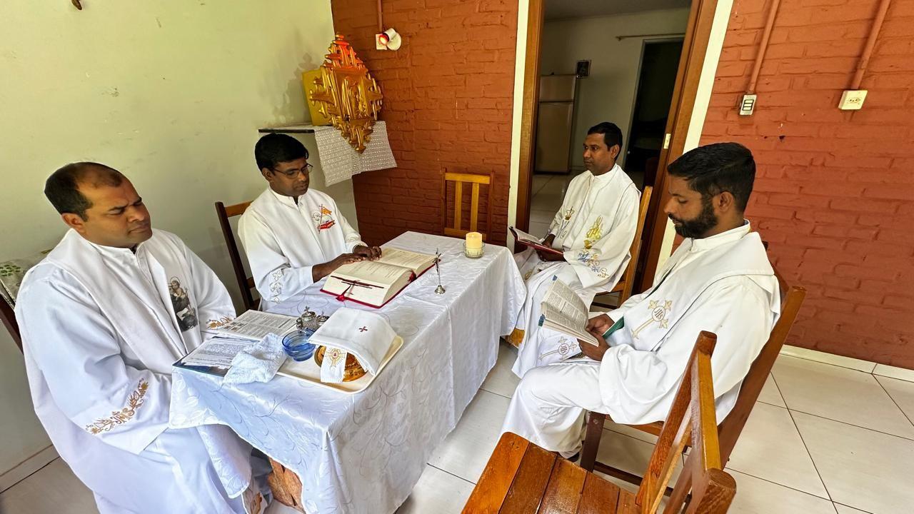 Quatro padres indianos sentado em mesa estudando  