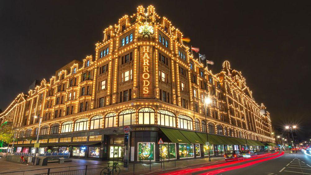 Prédio da Harrods iluminado durante a noite.