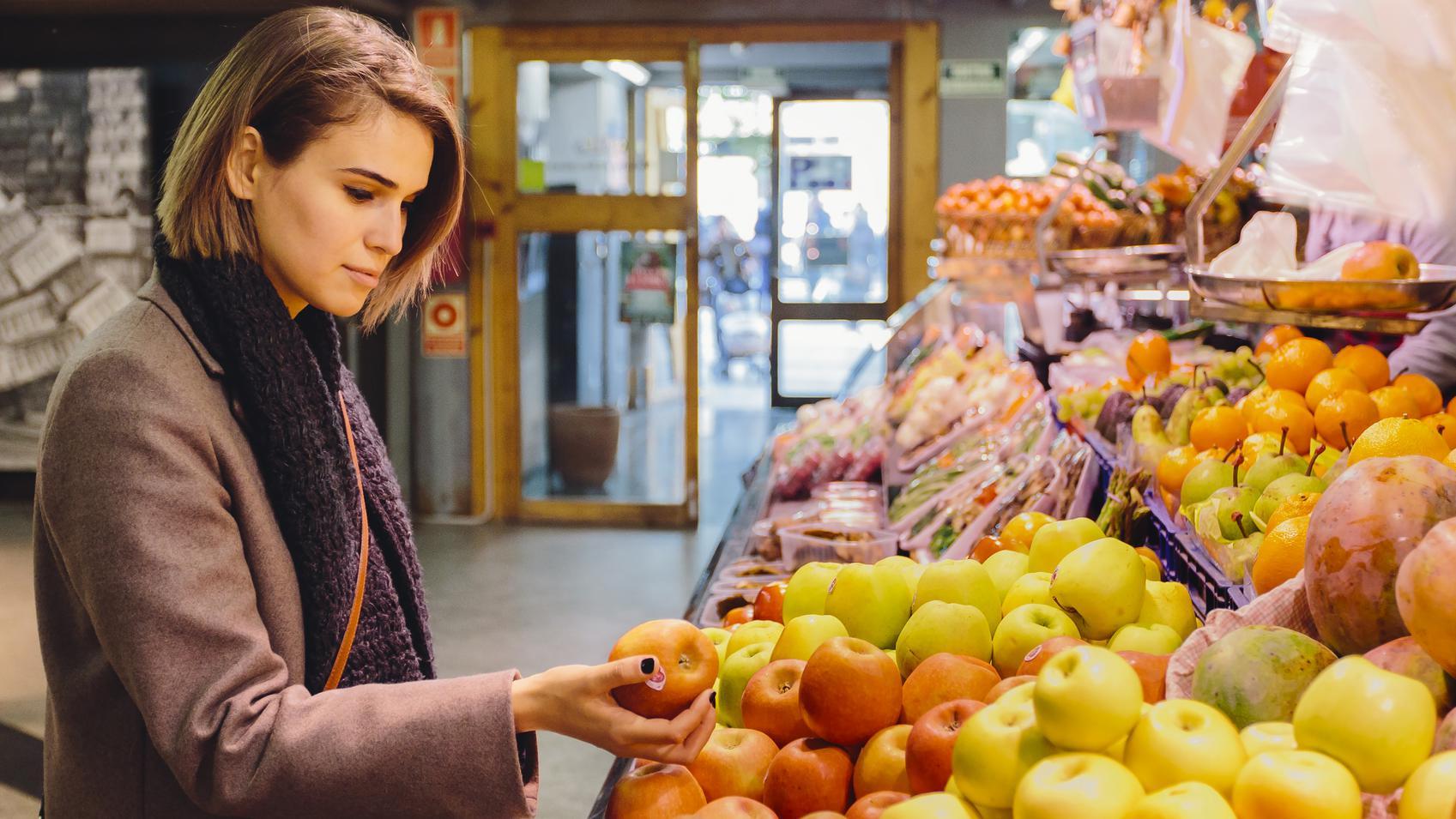 Mujer de compras en un puesto de frutas en un mercado