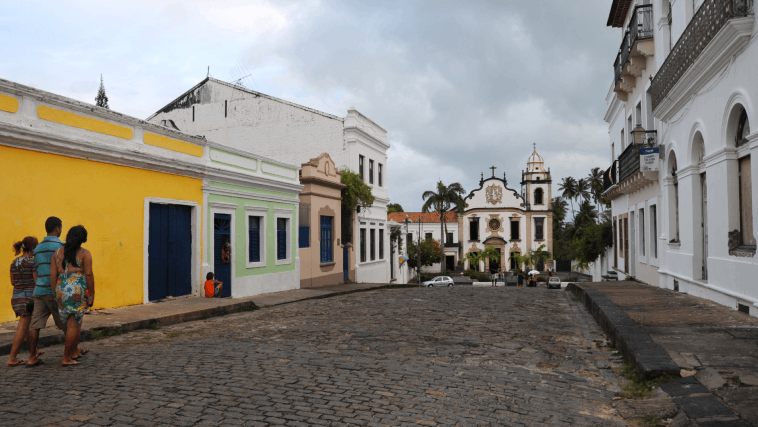 Varias personas caminan entre edificios coloridos en la ciudad de Olinda, en el noreste de Brasil, hacia la Basílica del Monasterio de San Benito.