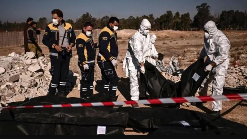 أفراد من الدفاع المدني السوري (الخوذ البيضاء) ينقلون أكياس جثث تحتوي على رفات بشرية تم انتشالها من مقبرة جماعية في دمشق