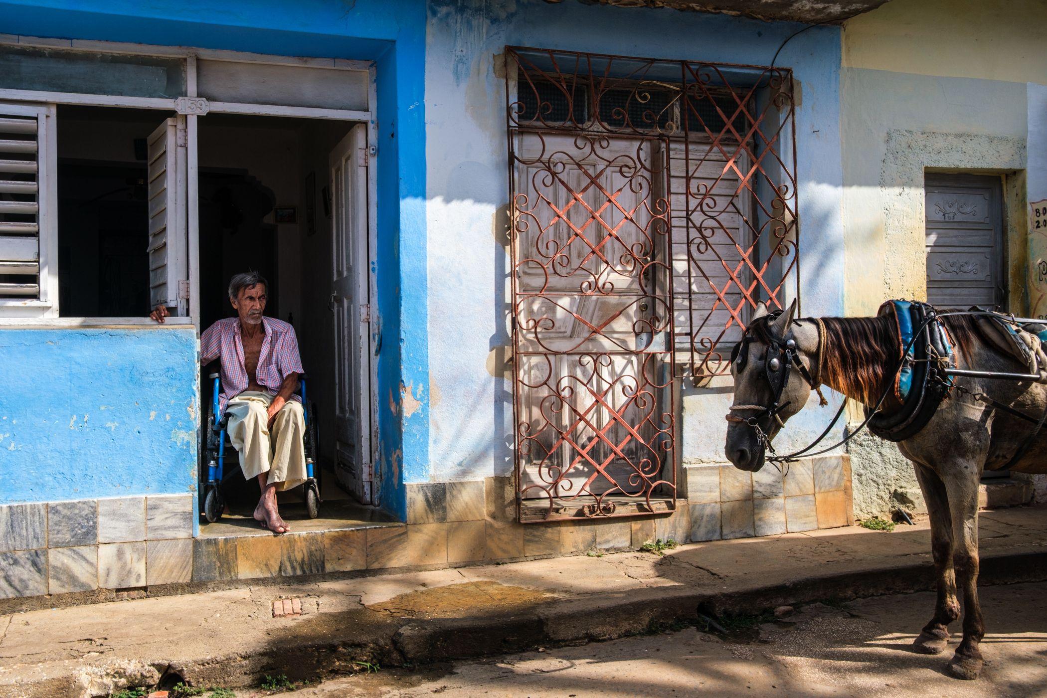 Un anciano discapacitado en la puerta de su hogar en Trinidad.