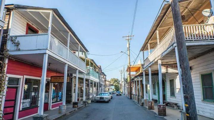 Imagem de uma rua estreita, com sobrados simples de madeira dos dois lados