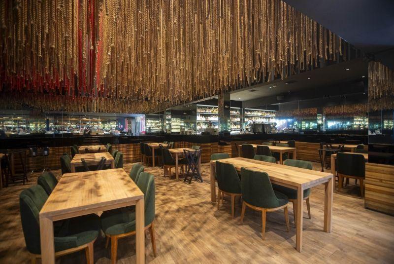 Restaurante com cadeiras verdes decorado com cordas no teto