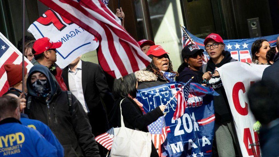 Apoiadores de Donald TRump carregam cartazes e bandeiras em seu favor