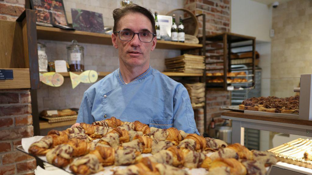 Koki kue Prancis, Stephane Louvard, berpose dengan "Crookies" buatannya, croissant tradisional Prancis yang dicampur dengan adonan cookie di toko kue miliknya di Paris, pada 2 April 2024.