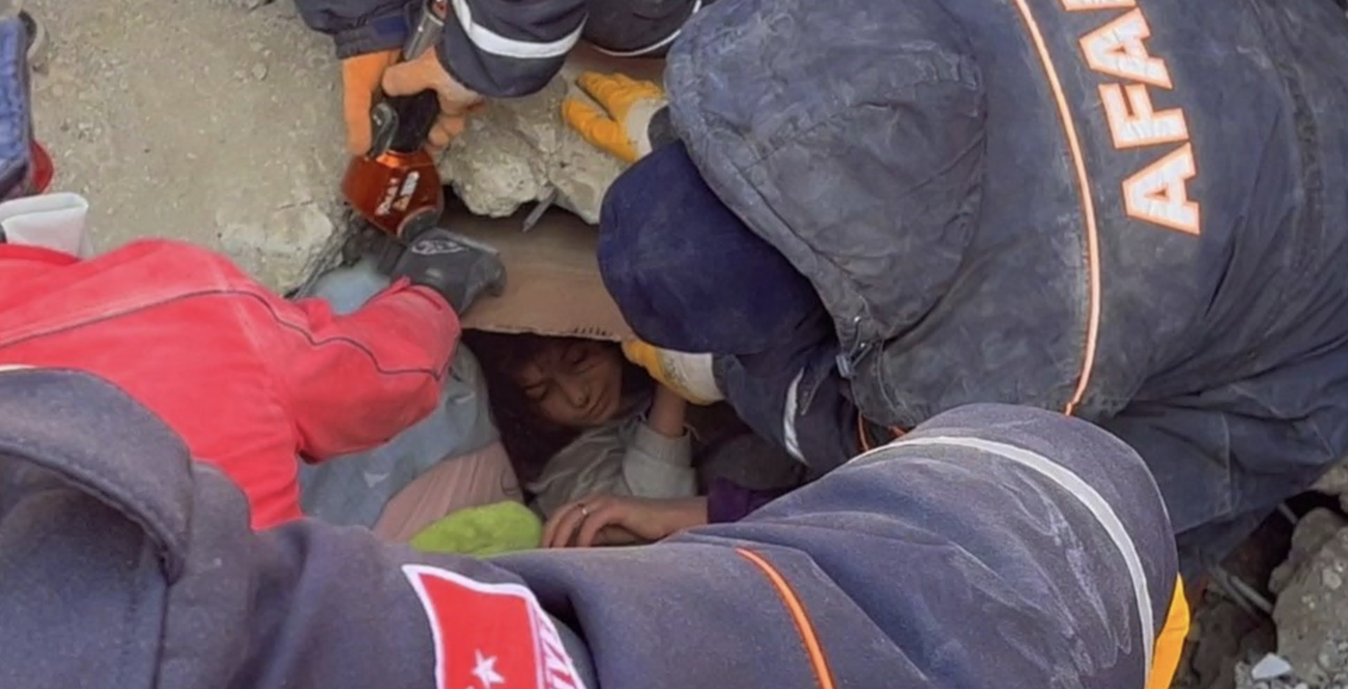 Menina sendo resgatada por socorristas dos escombros de um prédio desabado