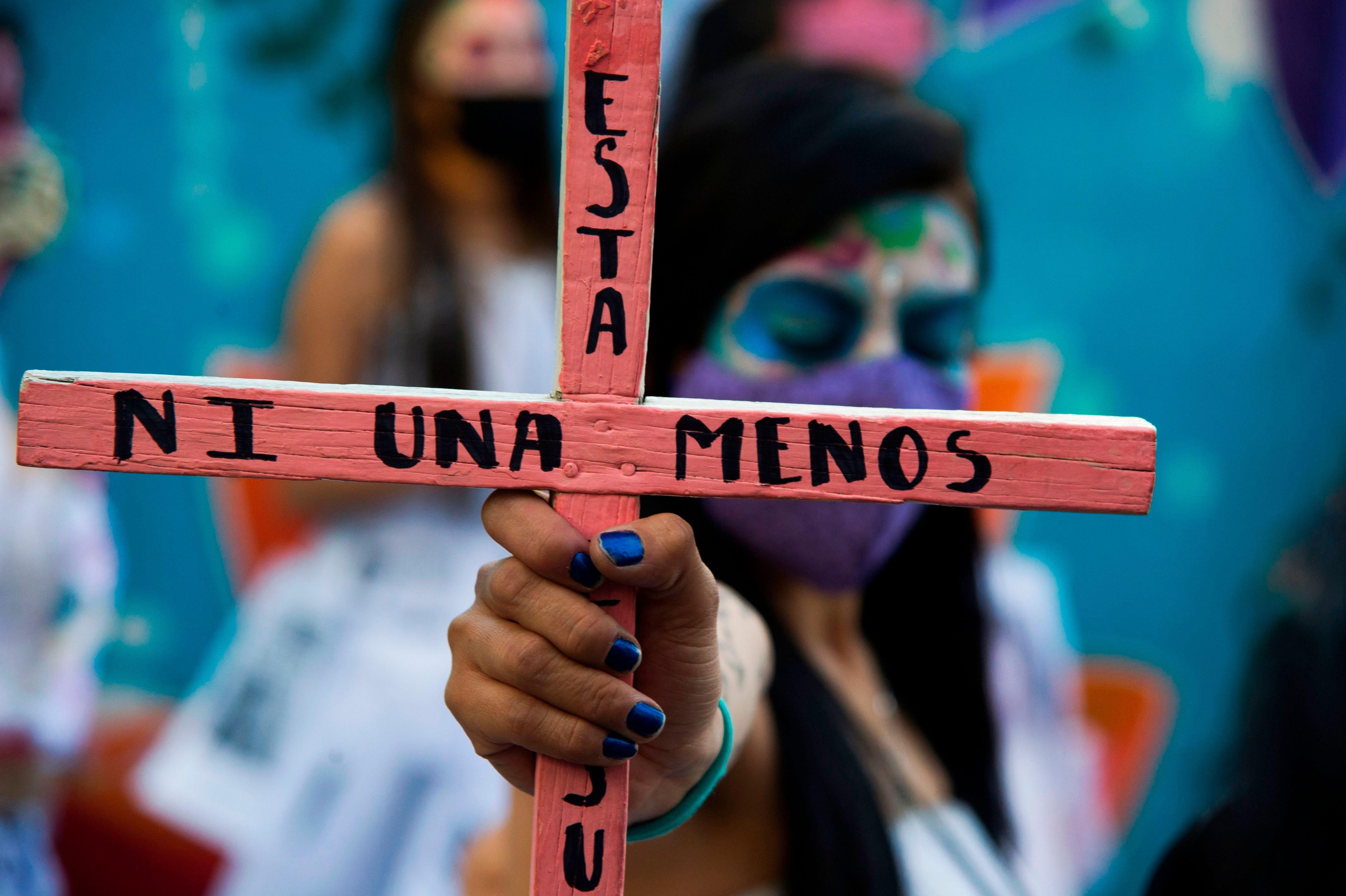 A woman holds a pink cross with the legend "Not one less" during a march against femicides in Mexico