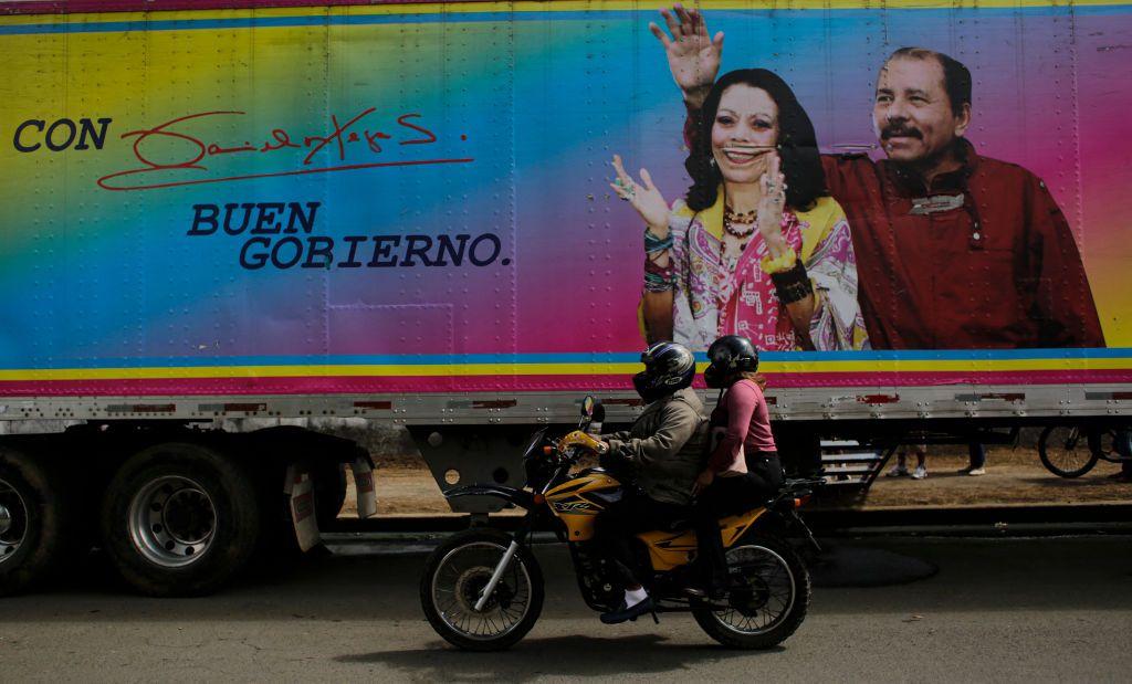 Un motociclista pasa junto a una pancarta del presidente de Nicaragua -y candidato presidencial- Daniel Ortega y su esposa y compañera de fórmula Rosario Murillo, colocada en una clínica móvil, en Masaya el 2 de noviembre de 2021.
