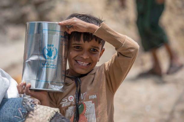 طفل يمني يحمل تنكة مساعدات من برنامج الأغذية العالمي
