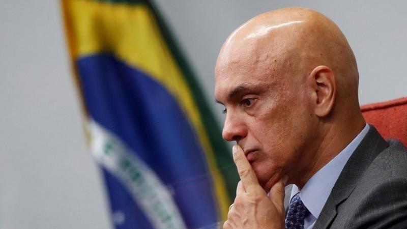 Alexandre de Moraes, um homem branco calvo, de terno e semblante sério, com olhar pensativo 