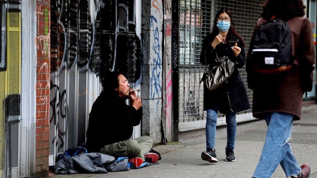 Un hombre fuma una pipa de heroína en la calle
