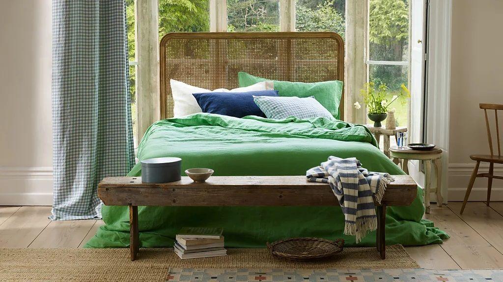 Cama com lençóis verdes em casa com detalhes de madeira