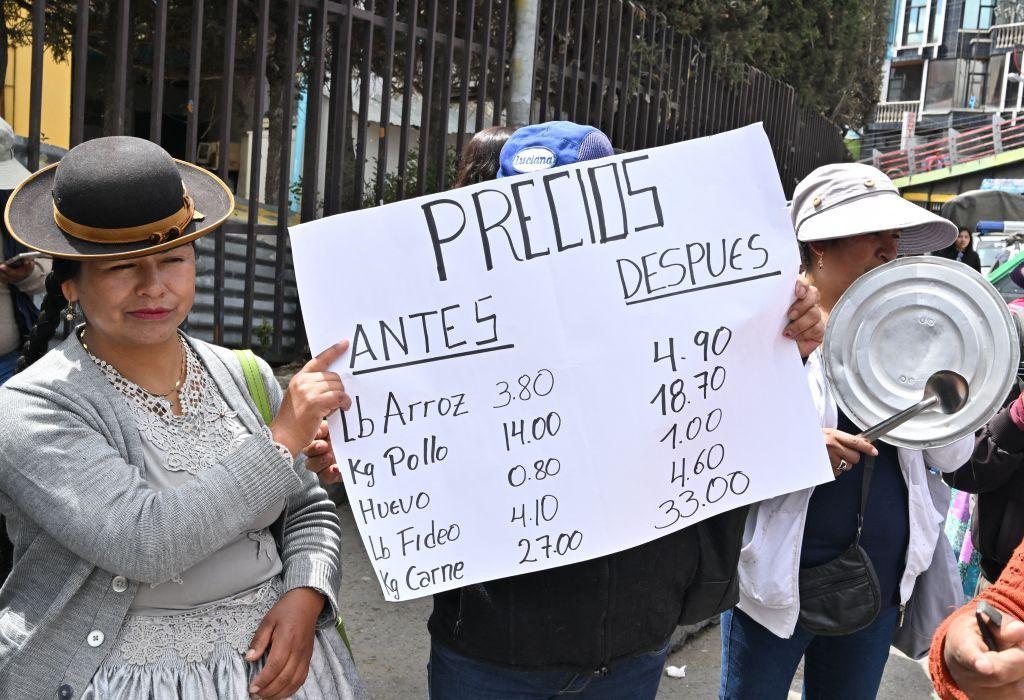 Manifestantes sostienen una pancarta con los precios de algunos alimentos básicos antes y después en Bolivia.