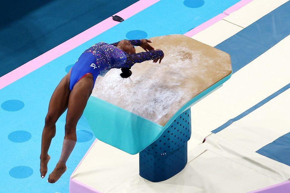 Simon Biles llegando de espaldas a la mesa