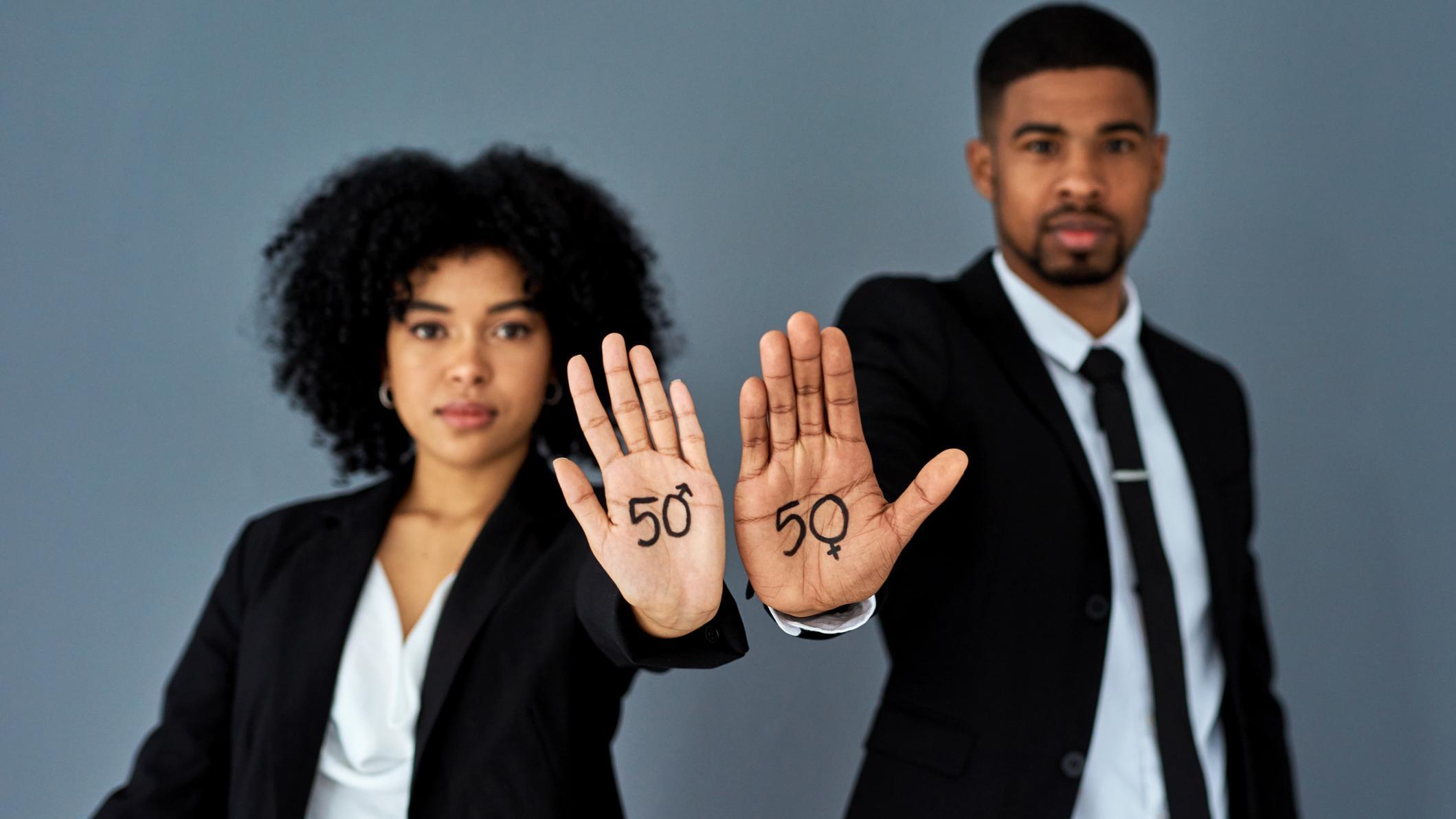Homem e mulher jovens negros de terno com a mão estendida onde está escrito 50