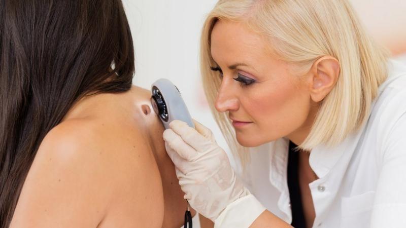 Una médico examina la piel de una paciente