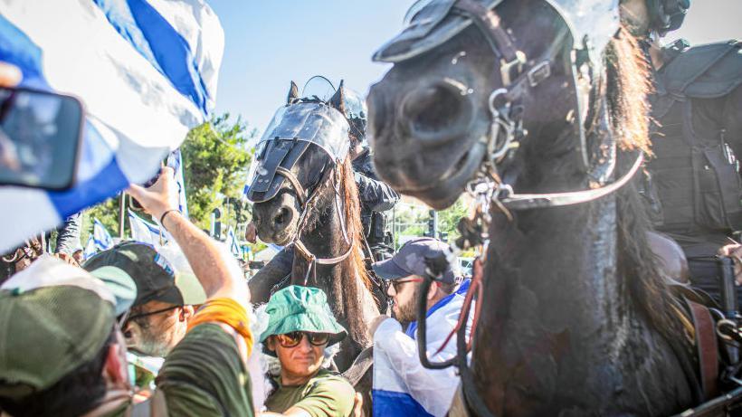 رجال شرطة إسرائيليون يمتطون الخيول قرب حشد من المتظاهرين الذين أغلقوا الطريق المؤدية إلى برلمان الكنيست الإسرائيلي، خلال مظاهرة مناهضة للتعديلات القضائية 