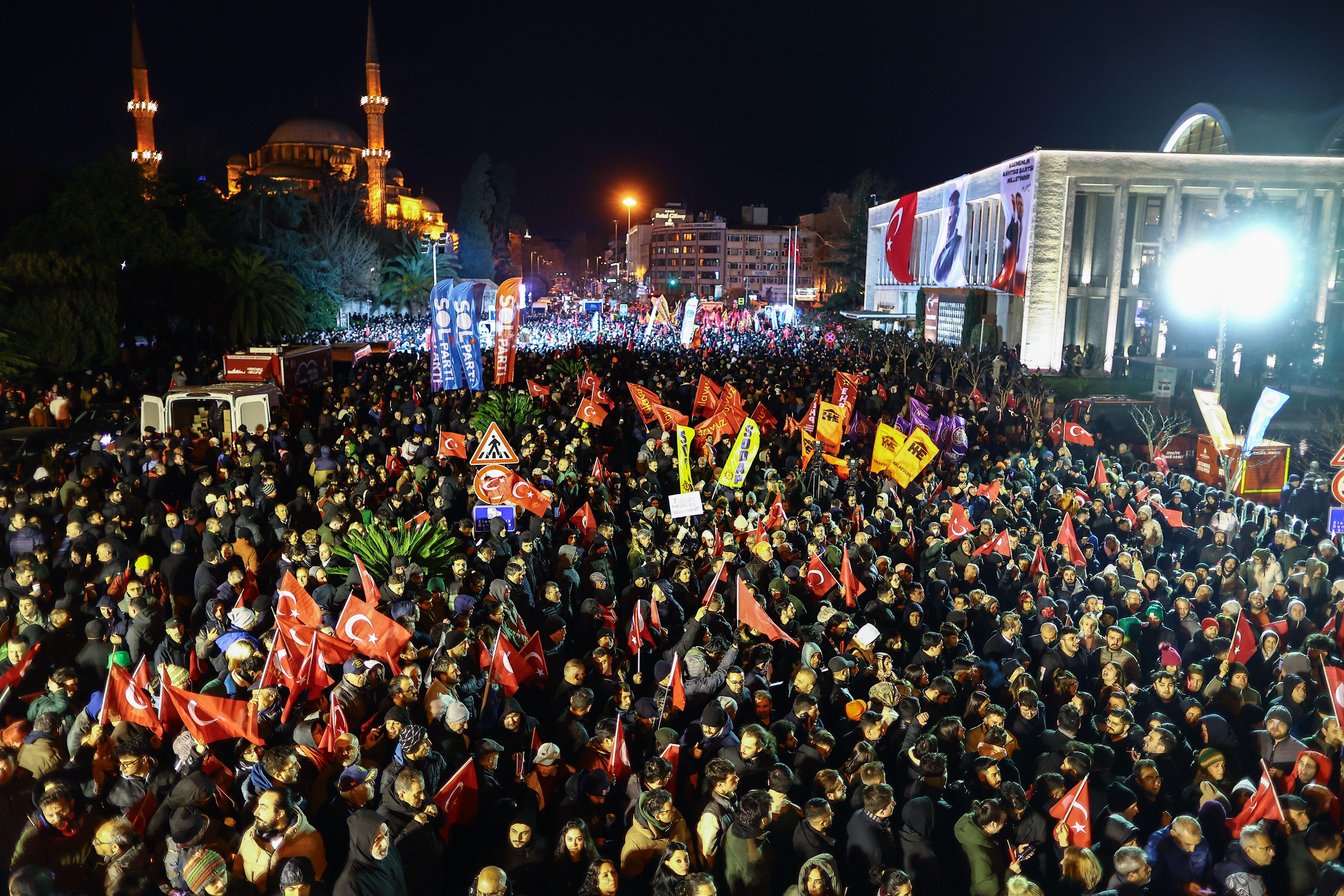 Crowds gathered at night waving flags outside Istanbul Municipality headquarters on 19 March 2025 