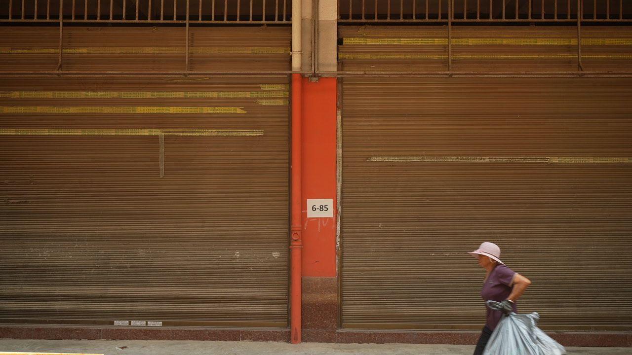 Una mujer pasa junto a tiendas cerradas en Ruili 