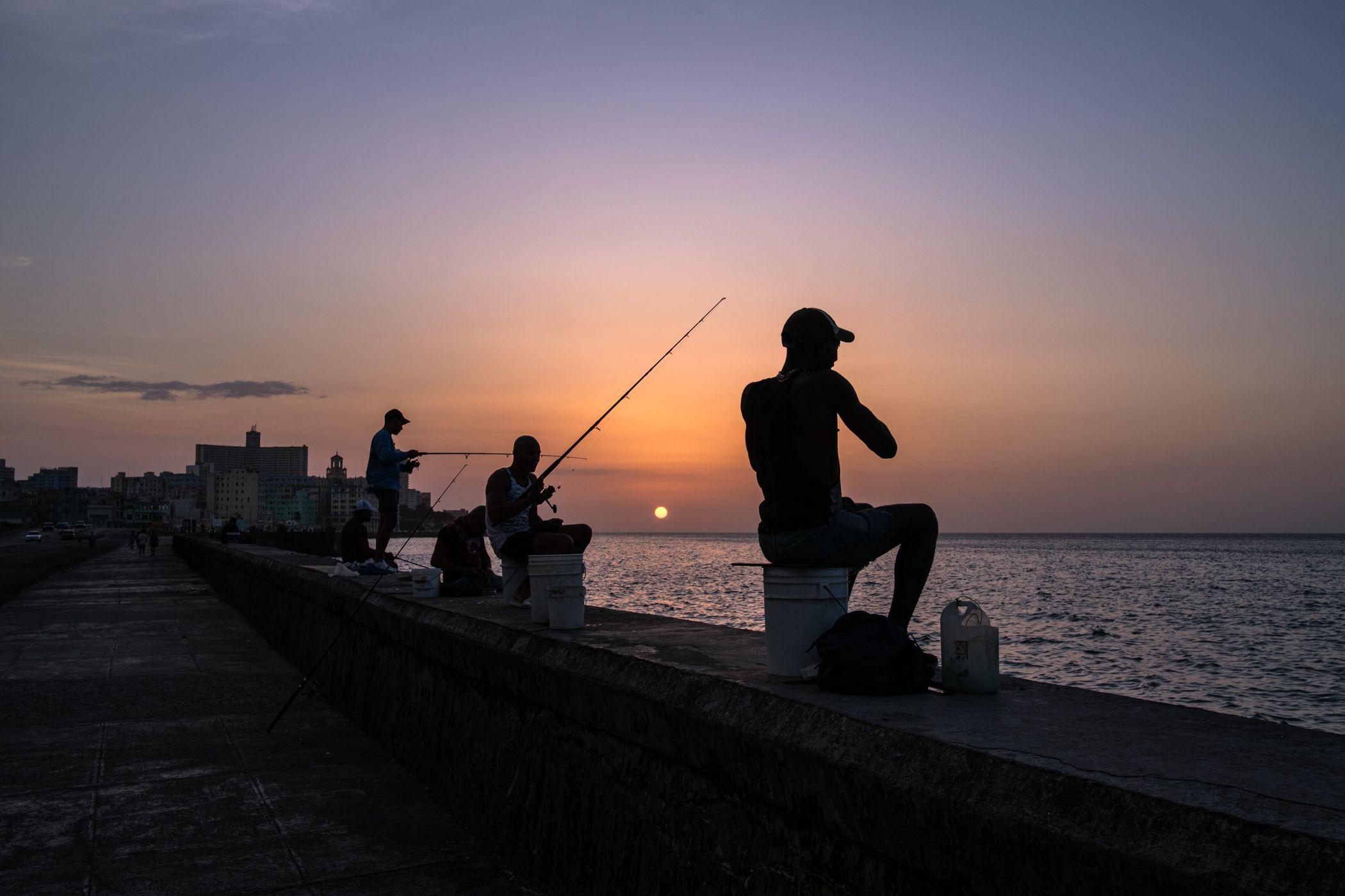 Un grupo de hombres pesca al atardecer. 