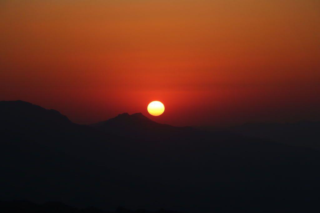 Atardecer con el sol y un cielo de un rojo intenso.