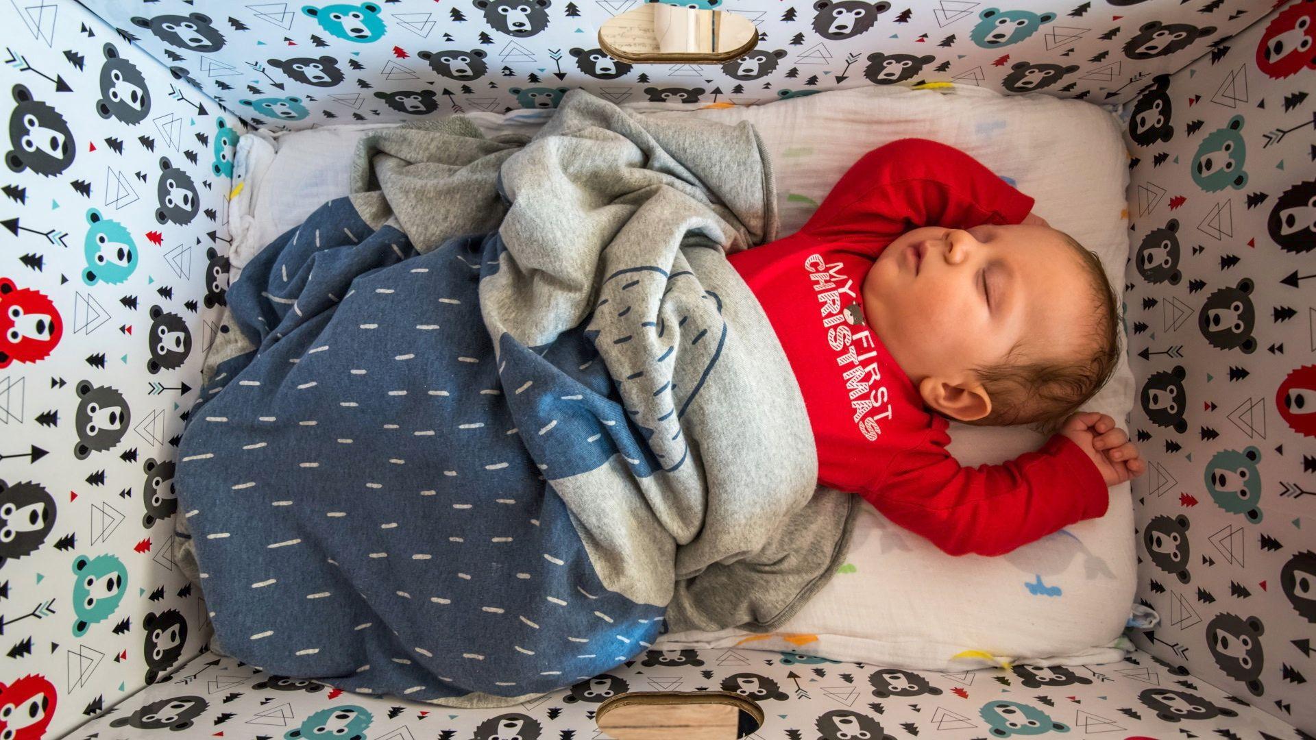 Bebê com roupa vermelha dormindo em uma caixa de papelão