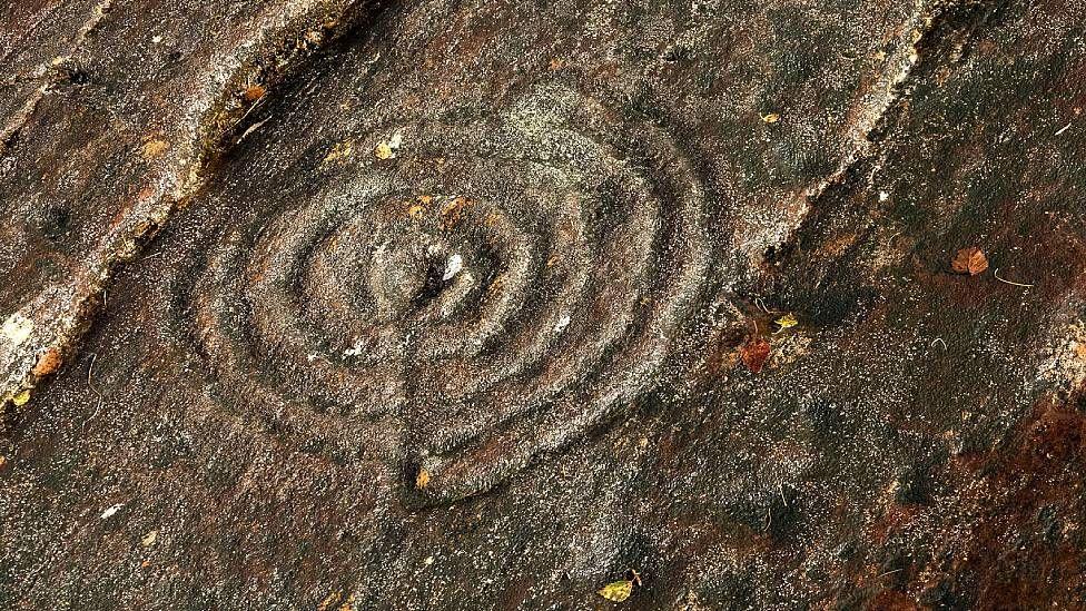 Círculos concêntricos esculpidos no solo de pedra em Kilmartin Glen