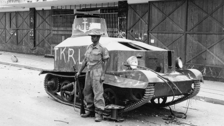 Seorang tentara India berdiri di depan tank bekas tentara Jepang yang digunakan oleh para pemuda Indonesia dalam Pertempuran Surabaya