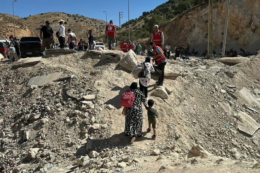 Sejumlah relawan orang-orang yang melarikan diri dari pemboman Israel di Lebanon saat mereka berjalan melintasi lokasi bekas pemboman di daerah Masnaa, Lebanon, 15 Oktober 2024. 