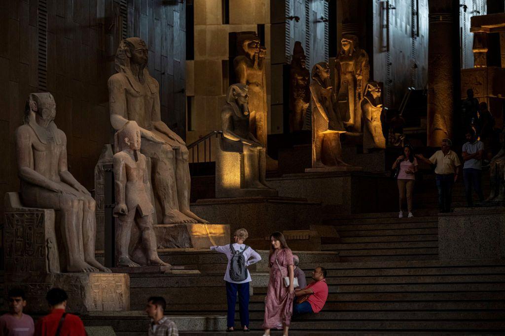 Pessoas caminham entre estátuas egípcias antigas na escadaria principal do Grande Museu Egípcio