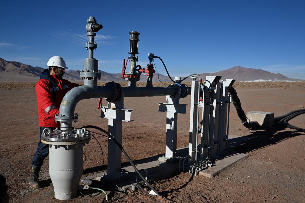 Trabalhador próximo a bombas e equipamentos no meio do deserto 