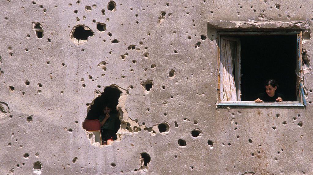 أم وطفلها في منزل تعرض لأضرار نتيجة الاشتباكات في حرب لبنان الأهلية