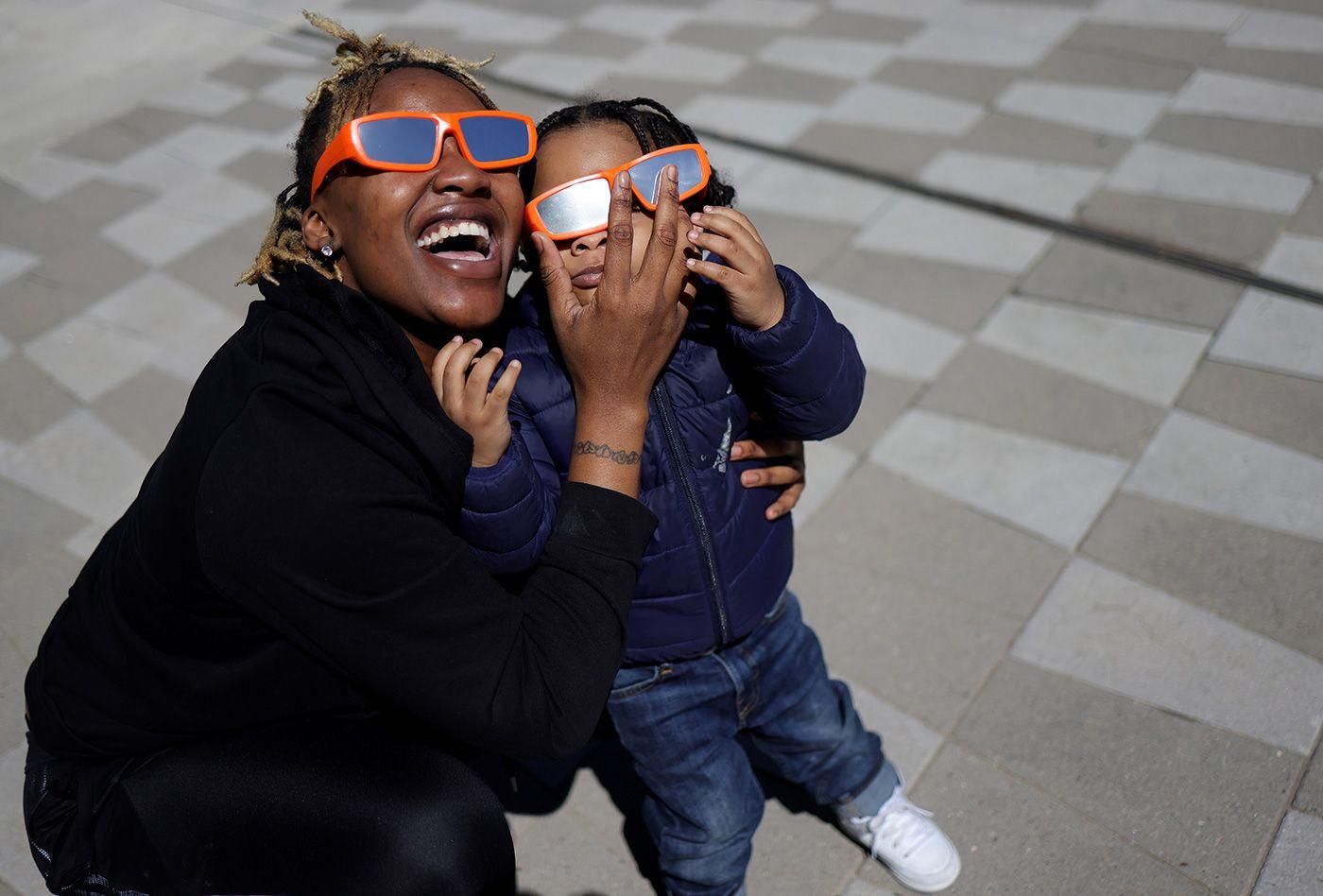 Mãe e filha observando o eclipse com óculos de proteção 