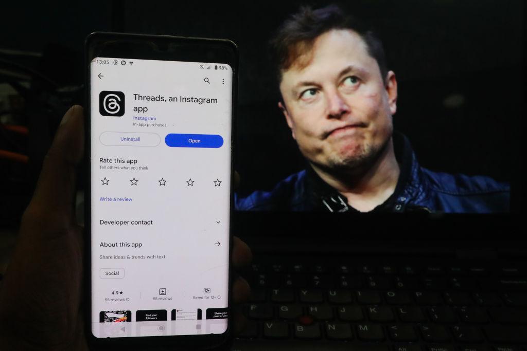 Elon Musk en la pantalla de una computadora y al frente un teléfono con Threads