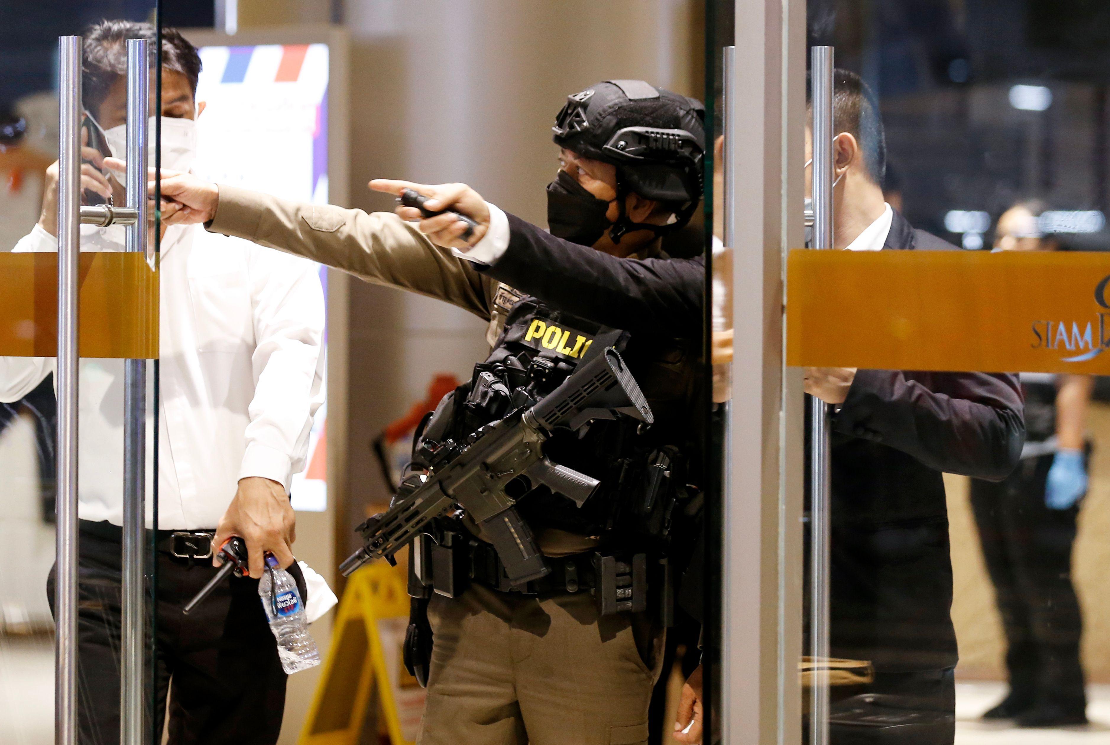 Polisi bersenjata berbicara dengan petugas keamanan di pintu masuk pusat perbelanjaan Siam Paragon, Bangkok
