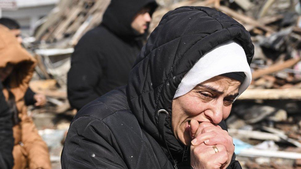 Uma mulher chora perto de um prédio desabado na cidade turca de Kahramanmaras (7 de fevereiro de 2023)