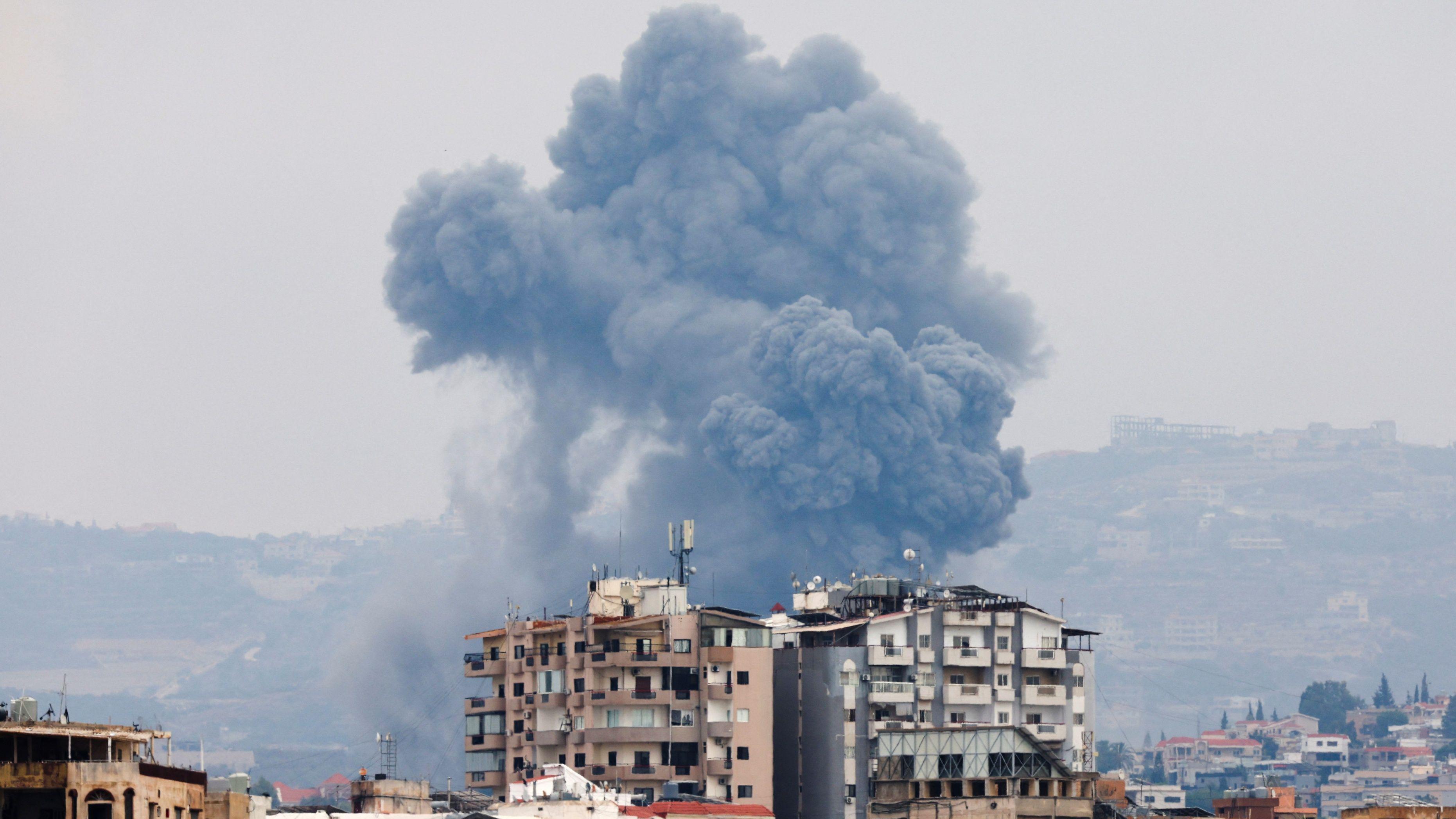 Smoke from Israeli shelling between buildings in Tire in southern Lebanon on October 7, 2024 