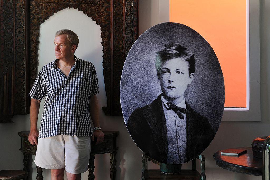 Penulis Jamie James berdiri di samping potret Arthur Rimbaud (1854-1891), di tokonya di Kerobokan, Bali. 