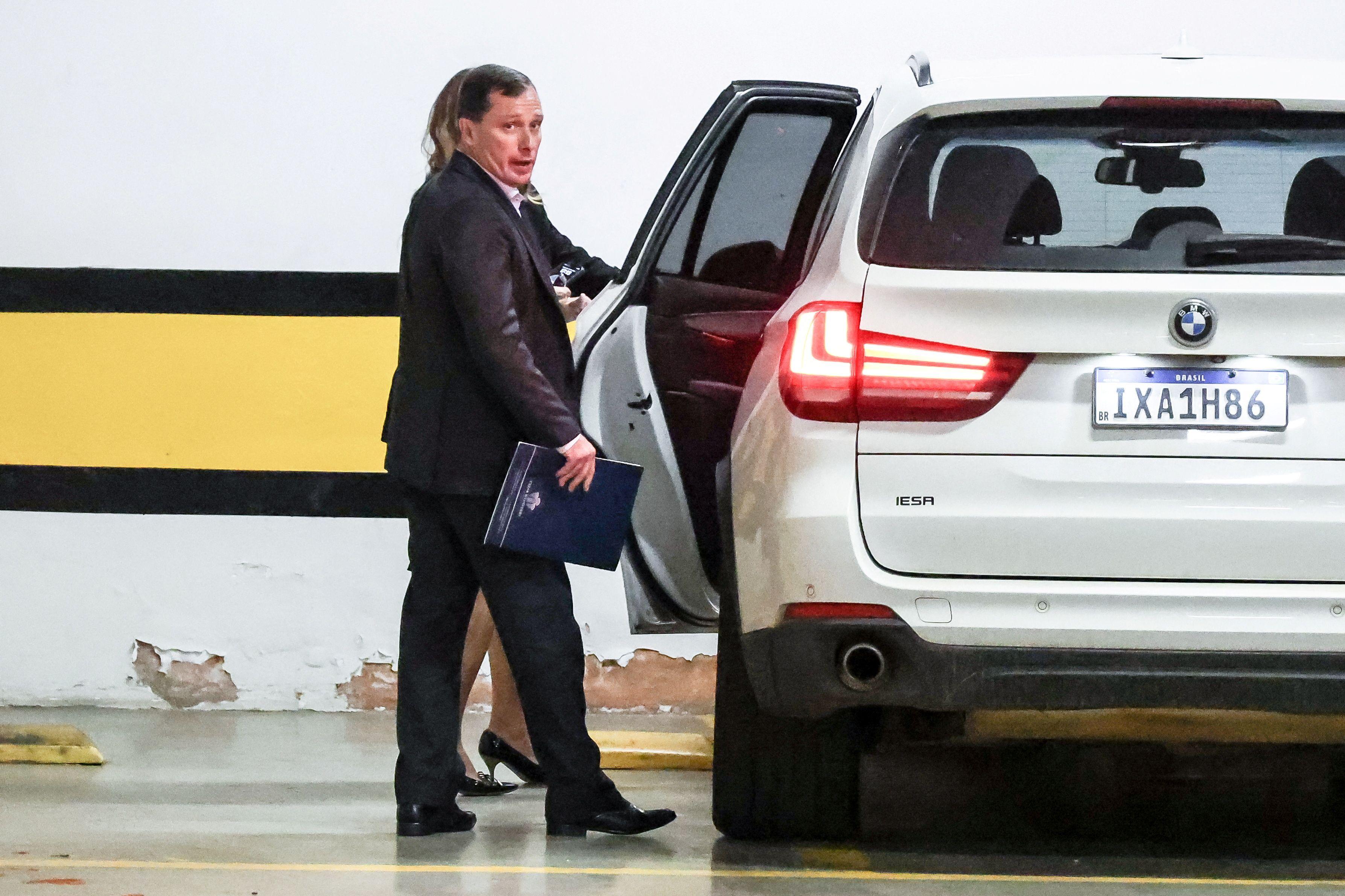 Mauro Cid, que foi assistente de Bolsonaro, deixa o prédio do Supremo Tribunal Federal. Ele está próximo a um carro prata, que está com a porta traseira aberta