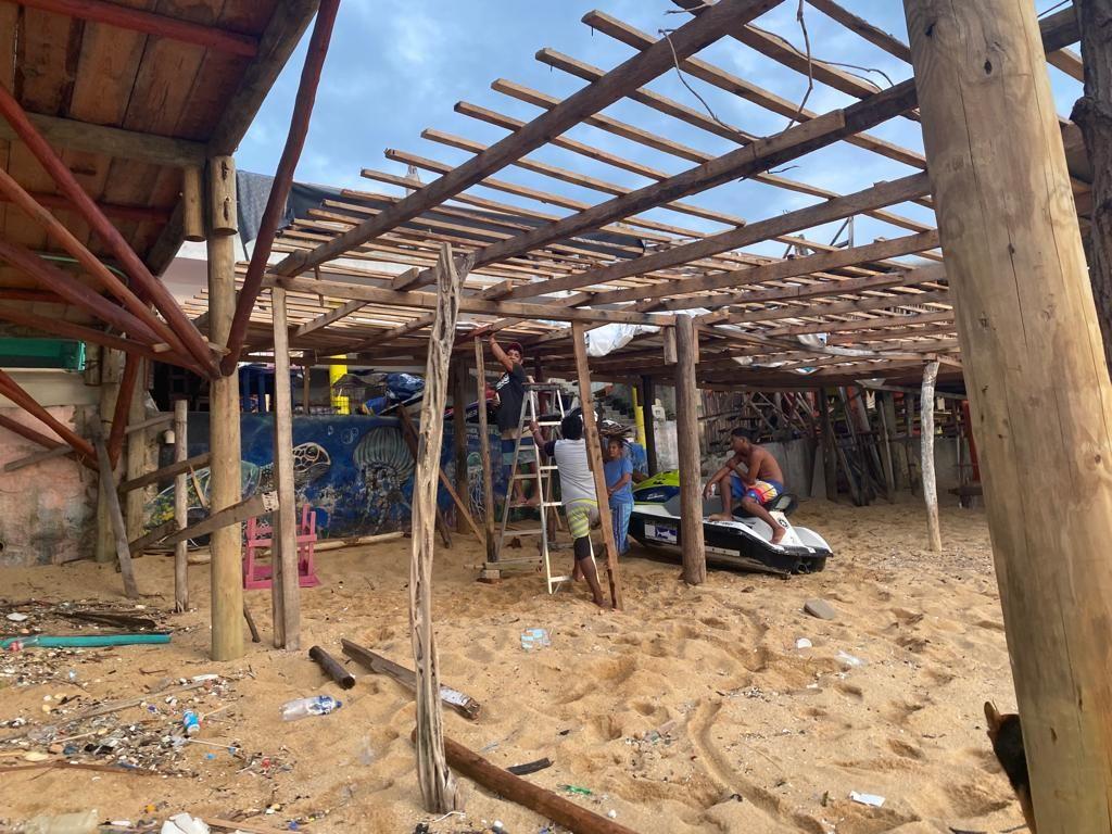 Hombres reparan un restaurante de playa en Acapulco
