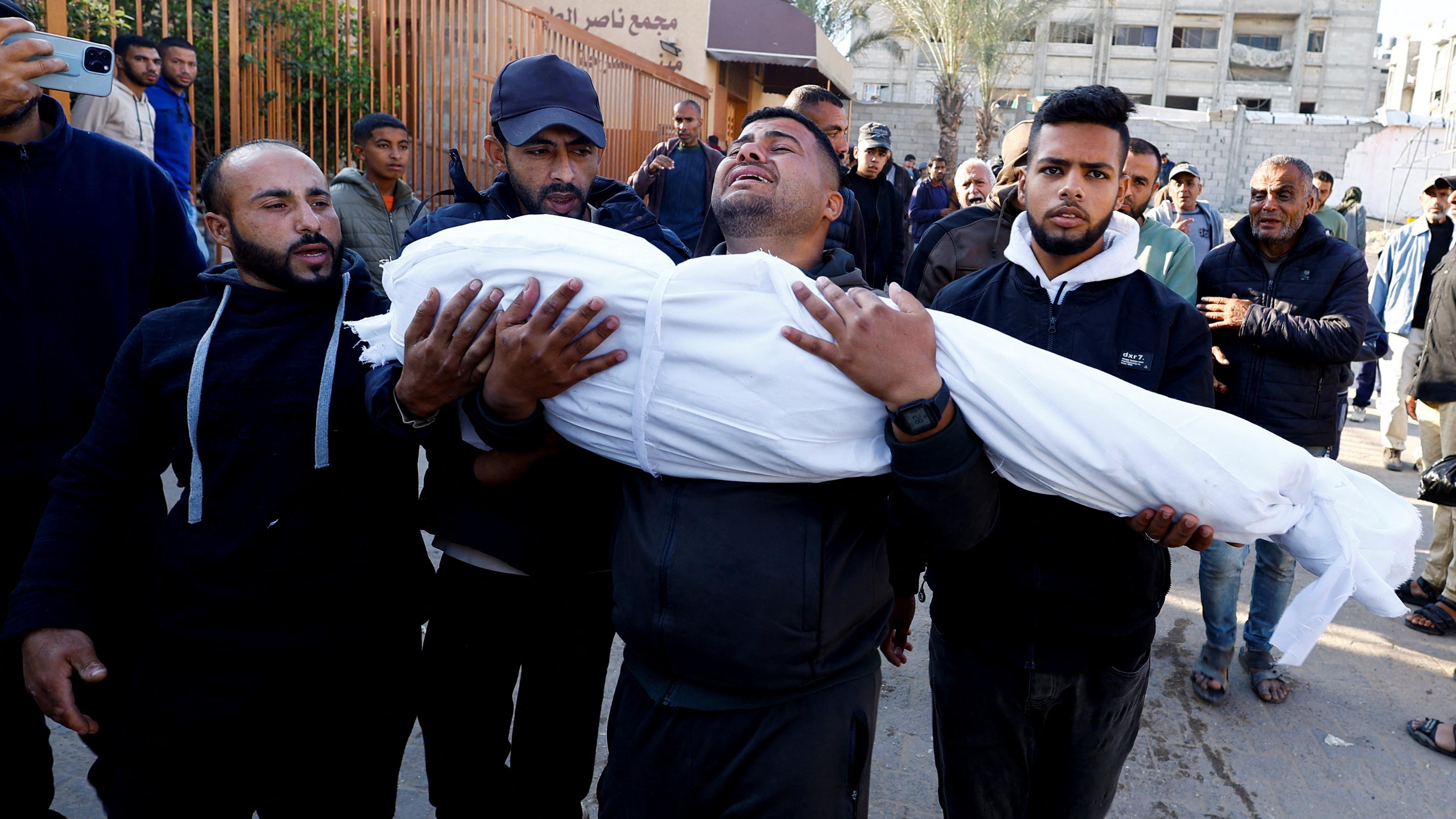 رجل يحمل جثة فلسطيني قُتل في غارة إسرائيلية، في مستشفى ناصر في خان يونس جنوب قطاع غزة، 23 نوفمبر/ تشرين الثاني 2024. 