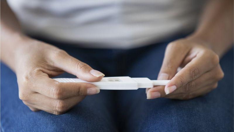 Mulher segurando teste de gravidez