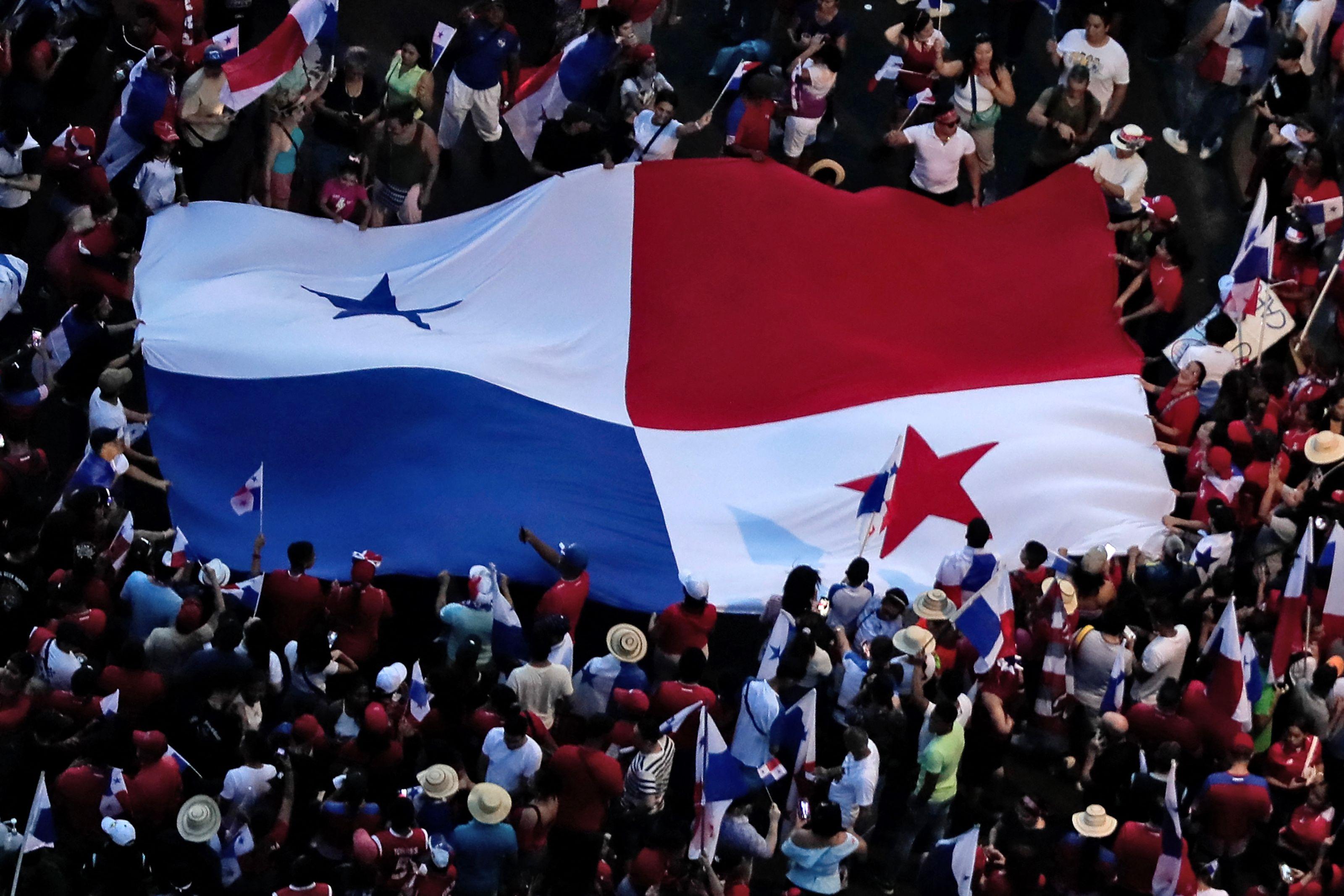 Personas celebran alrededor de una gran bandera de Panamá