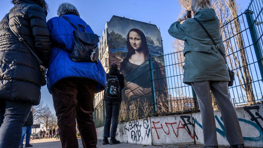 Pessoas tiram foto de um mural em Berlim que reproduz a Mona Lisa de Da Vinci