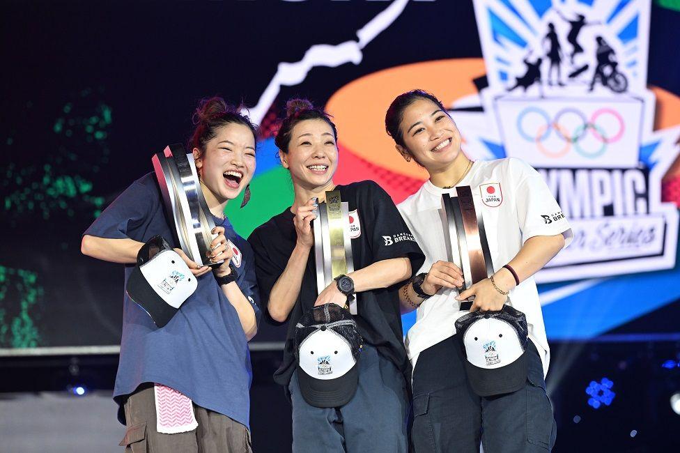 Tres atletas japonesas sonríen con sus trofeos