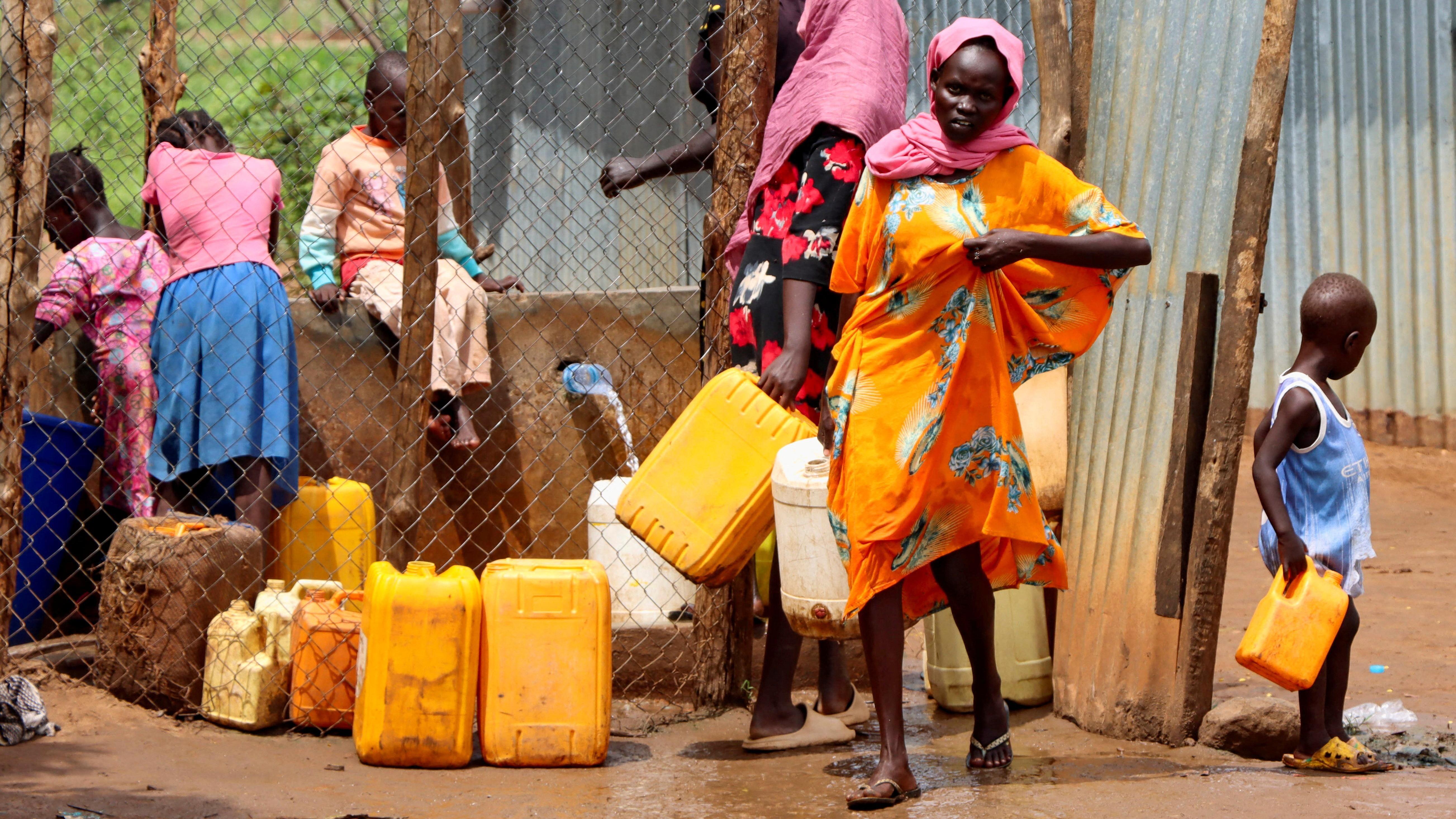 لاجئون سودانيون يجمعون المياه من صنبور في مخيم غوروم للاجئين الذي يستضيف اللاجئين السودانيين في اليوم العالمي للاجئين، للاحتفال بقوة وشجاعة الأشخاص الذين أجبروا على الفرار من وطنهم هربًا من الصراع تحت شعار "الأمل بعيدًا عن الوطن" بالقرب من جوبا، في جنوب السودان.